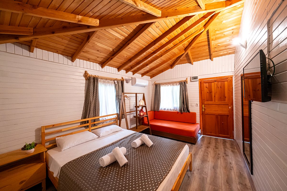 Bungalow Oda: ahşap tavanlı oda, çift kişilik yatak ve kırmızı kanepe