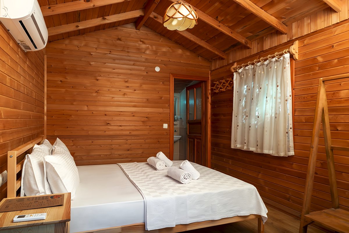 Ahşap duvarlı bungalov odası, beyaz nevresimli yatak